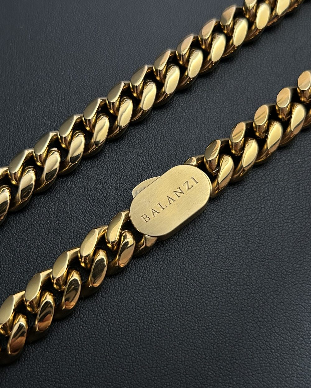 The BALANZI clasp tag on the 12mm Cuban link, close up on black leather